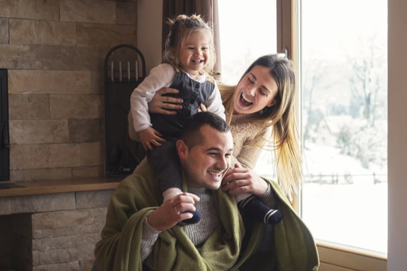 Limited Time Carrier Savings: Enjoy a 0 Trade-In Allowance on a New Furnace. Young family on winter vacation, looking through window.